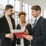 Business professionals discussing a car lease or purchase agreement in a showroom setting.